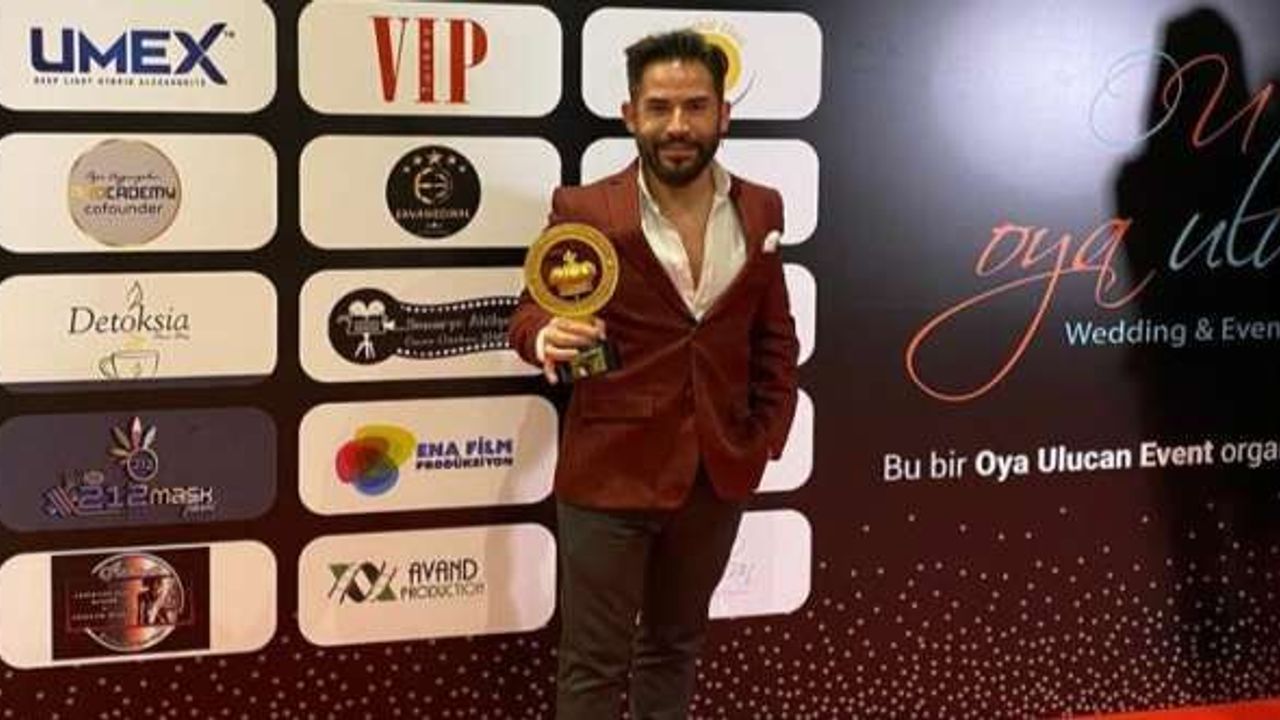 Ali Akduru holding an award in the photograph published with his 2022 career profile